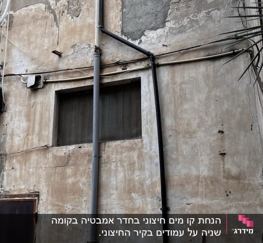 קיר עם צינורות פלסטיק וחלון קטן